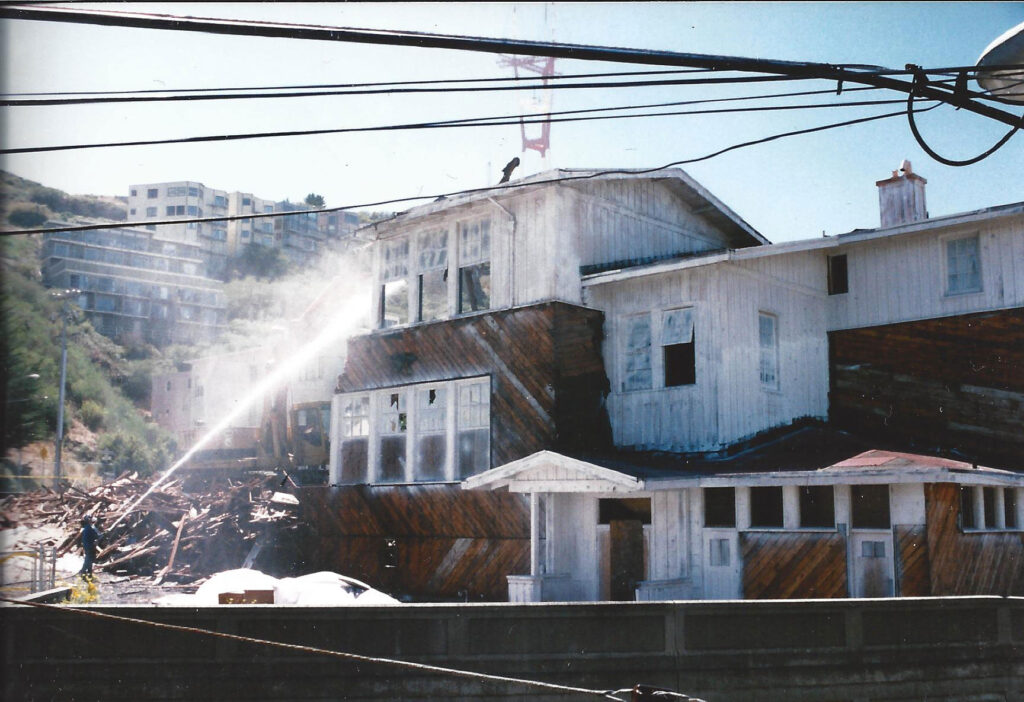 Construction workers hose down dust and debris during the demolition of the original Twin Peaks School building. 